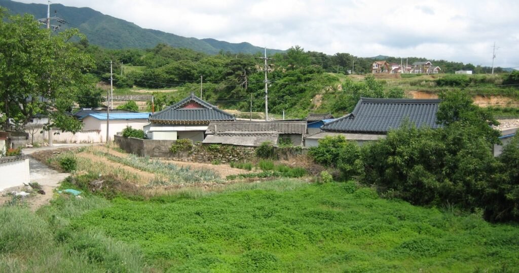 Small rural village with tiled-roof houses, vegetable fields and green hills in the South Korean countryside