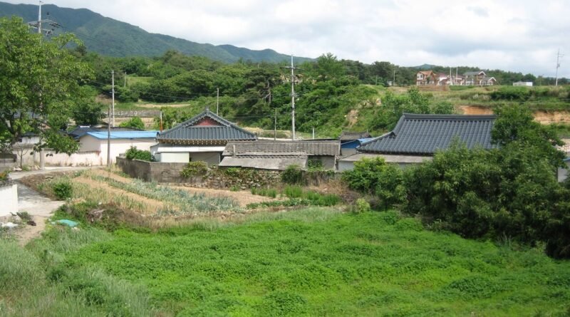 Small rural village with tiled-roof houses, vegetable fields and green hills in the South Korean countryside